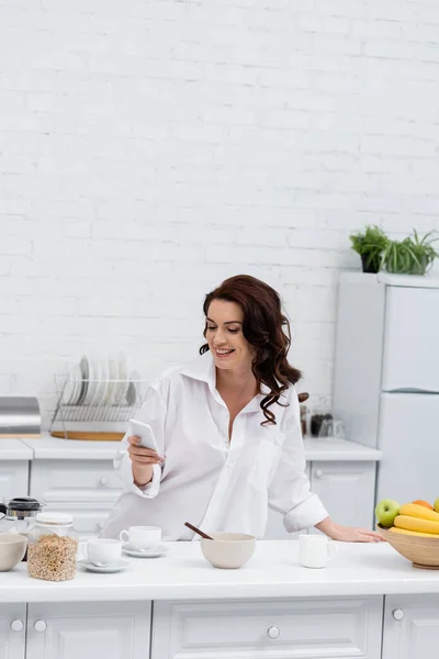 Mujer Morena Sonriente Camisa Usando Smartphone Cerca Anillos Cereales Café —  Fotos de Stock