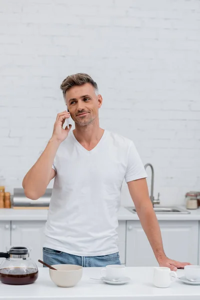 Hombre Sonriente Camiseta Hablando Teléfono Inteligente Cerca Café Cocina — Foto de Stock