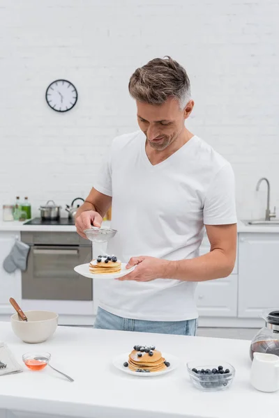 Glimlachende Man Gieten Poedersuiker Heerlijke Pannenkoeken Buurt Van Koffie Honing — Stockfoto