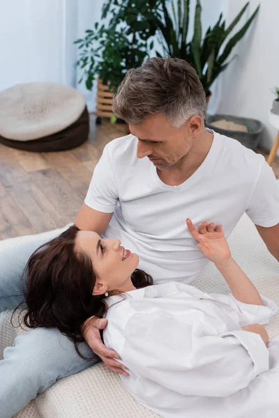 早上穿着白衬衫躺在床上拥抱积极妻子的男人 — 图库照片