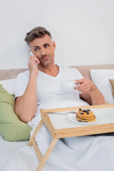 Homem Falando Smartphone Segurando Xícara Café Perto Panquecas Borradas Bandeja — Fotografia de Stock