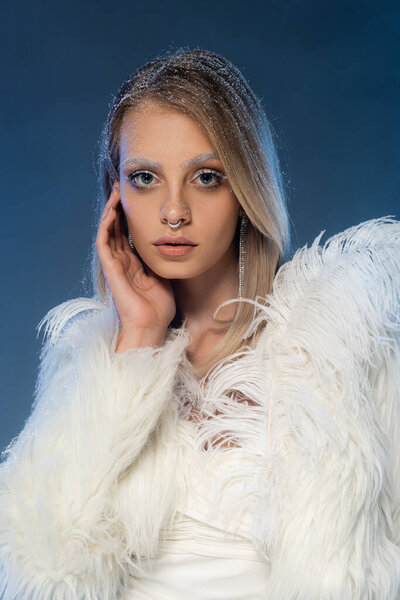 young pierced woman with snow on hair and white eyebrows on dark blue 