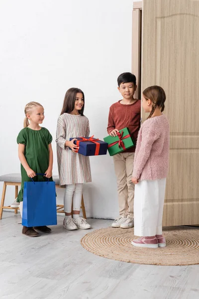 Alegre Interracial Niños Sosteniendo Regalos Cerca Amigo Puerta Casa — Foto de Stock