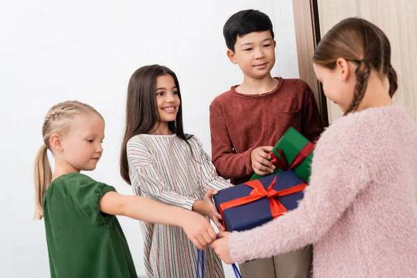 Niños Multiétnicos Dando Regalos Amigo Borroso Casa —  Fotos de Stock