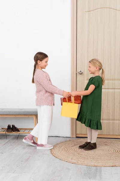 Side View Smiling Kid Giving Present Shopping Bag Friend Home — Stock Photo, Image