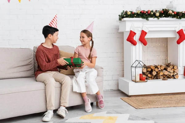 Asian Boy Party Cap Holding Present Friend Couch Christmas Decor — Stock Photo, Image