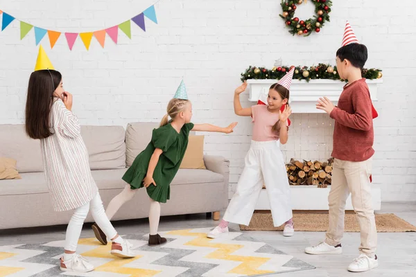 Interracial kids playing tag during birthday party in winter at home