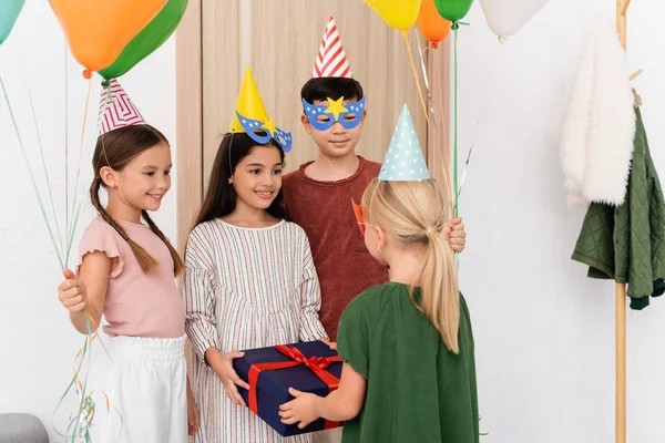 Alegre Interracial Niños Sosteniendo Regalo Globos Cerca Amigo Pasillo Casa — Foto de Stock