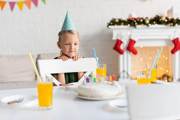 Niño Gorra Fiesta Mirando Vasos Con Jugo Naranja Pastel Cumpleaños — Foto de Stock