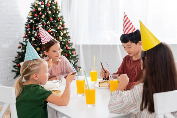 Niños Multiétnicos Gorras Fiesta Celebrando Cumpleaños Cerca Pastel Jugo Naranja — Foto de Stock