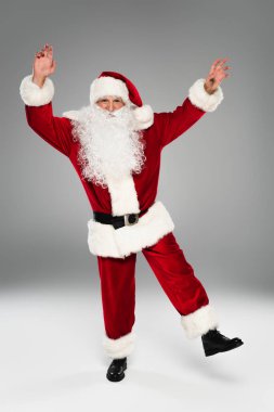 Gri arka planda kostümlü Noel Baba dansı. 