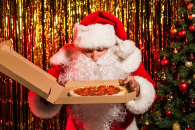 Santa claus in hat holding takeaway pizza near christmas tree and tinsel  clipart