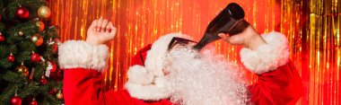 Father christmas in sunglasses drinking champagne from bottle near tinsel, banner  clipart