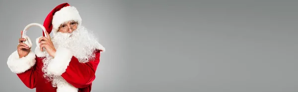 Mikołaj Brodą Trzymający Słuchawki Bezprzewodowe Izolowane Szarym Szarym Banerze — Zdjęcie stockowe