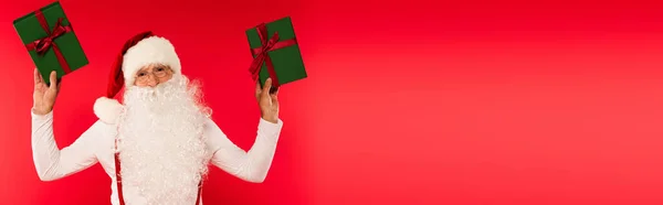 Weihnachtsmann Mit Brille Und Hut Hält Geschenke Isoliert Auf Rot — Stockfoto