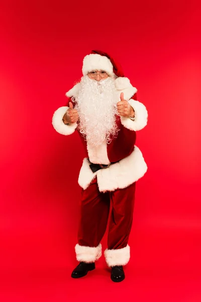 Санта Клаус Очках Показывает Жест Перед Камерой Красном Фоне — стоковое фото