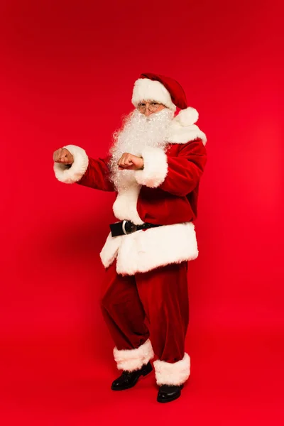 Vousatý Santa Claus Při Pohledu Kameru Při Tanci Červeném Pozadí — Stock fotografie