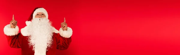 戴着眼镜的圣诞老人用手指指尖向上看红色背景 高举旗帜 — 图库照片
