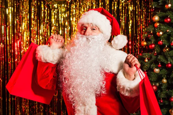圣诞佳节前夕 圣诞老人身着盛装 提着购物袋来到圣诞树旁和金银花旁 — 图库照片