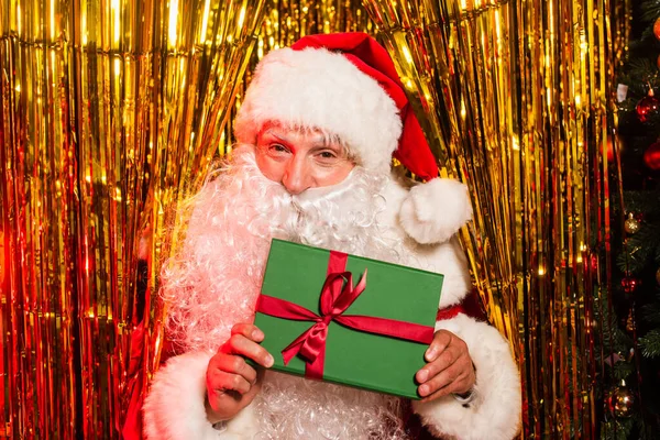 Father Christmas Hat Holding Gift Bow Shiny Tinsel — Stock Photo, Image