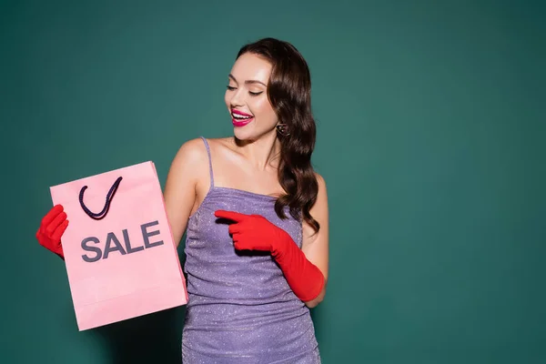 Happy Young Woman Red Gloves Purple Dress Pointing Shopping Bag — Stock Photo, Image