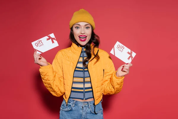 Jovem Mulher Espantada Chapéu Gorro Jaqueta Puffer Laranja Segurando Cartões — Fotografia de Stock