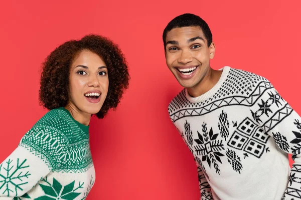 穿着冬季毛衣 头戴装饰品 看着红色相机的兴奋的非洲裔美国夫妇 — 图库照片