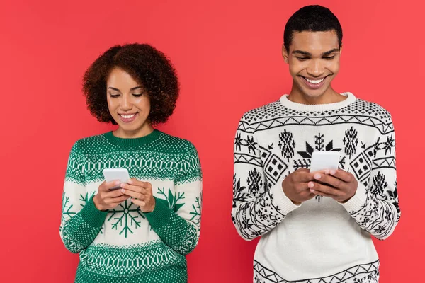 Smiling African American Couple Sweaters Winter Pattern Chatting Smartphones Isolated — Stock Photo, Image