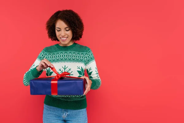 陽気なアフリカ系アメリカ人女性オープンクリスマスプレゼントにブルーギフトボックスに隔離された赤 — ストック写真