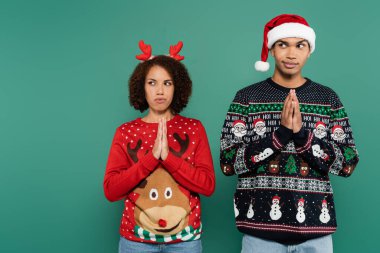 Gergin Afrikalı Amerikalı çift Noel kıyafetiyle dua eden ellerle dikiliyor ve yeşil ışıkta yalnız başına gözlerini kaçırıyor.