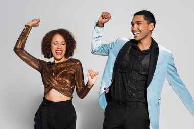 Heyecanlı Afro-Amerikan çifti zarif giysiler içinde yılbaşı partisinde dans ediyorlar. Gri renkte.