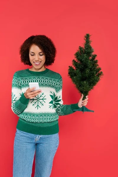 Lächelnde Afroamerikanerin Warmen Pullover Mit Kleinem Weihnachtsbaum Und Handy Auf — Stockfoto