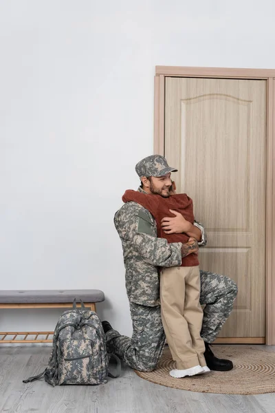 Feliz Militar Abrazando Hijo Cerca Mochila Puerta Entrada Casa — Foto de Stock