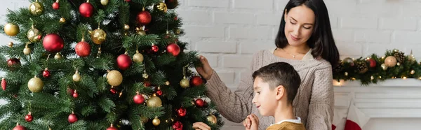 Brunette Vrouw Glimlachen Buurt Zoon Versieren Groene Sparren Met Kerstballen — Stockfoto