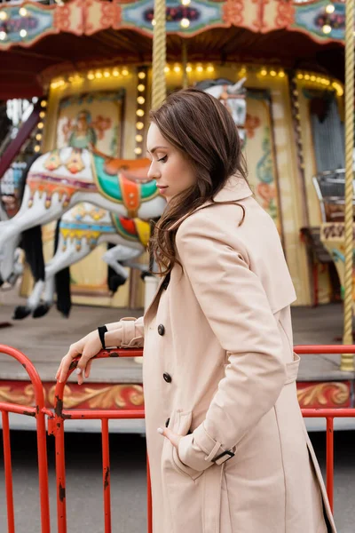 Young Woman Beige Trench Coat Standing Carousel Amusement Park — Stock Photo, Image