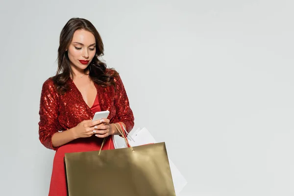드레스를 스마트폰을 사용하고 회색에 고립된 쇼핑백을 — 스톡 사진