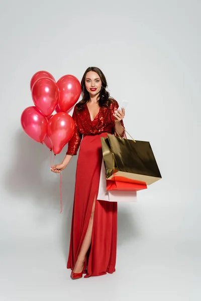 Full Length Woman Red Dress Holding Smartphone Balloons Grey Background — Stock Photo, Image