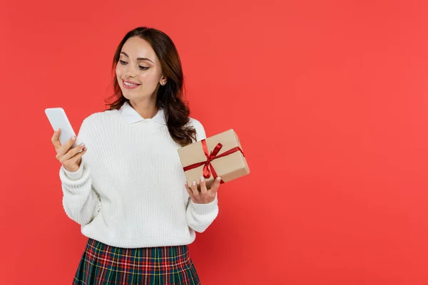 Cheerful Woman Jumper Using Smartphone Holding Gift Box Isolated Red — Stock Photo, Image