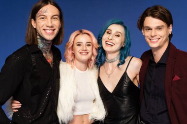 Dövmeli ibne kameraya bakıyor modaya uygun ve neşeli olmayan arkadaşlar mavi üzerine izole edilmiş.