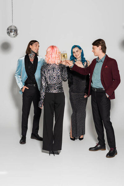 полная длина стильных небинарных друзей звон бокалов шампанского на сером фоне