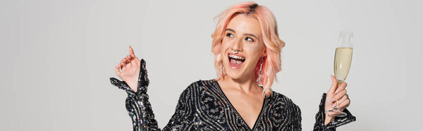 взволнованная женщина с шампанским и глядя в сторону изолированы на серый, баннер