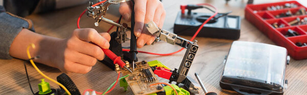 Cropped view of child making robotic model with millimeter at home, banner 
