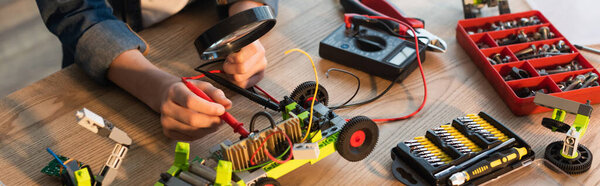 Обрезанный вид на ребенка с лупой рядом с роботизированной моделью и миллиметром дома, баннер 