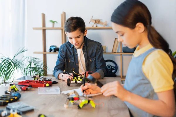 Çocuk Bulanık Kızın Yanında Robotik Modeller Kuruyor Defterinde Büyüteç Var — Stok fotoğraf