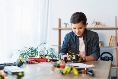 ergen çocuk bulanık arkaplanda mekanik detayların yanında robot modeli monte ediyor