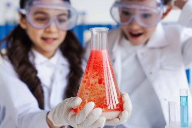 Bulanık arka planda, şaşkın arkadaşlarının yanında köpüklü kırmızı sıvılı mataranın seçici odağı