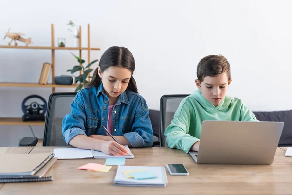 Çocuk Dizüstü Bilgisayar Kullanıyor Kız Akıllı Telefonun Yanında Yazıyor Evde — Stok fotoğraf