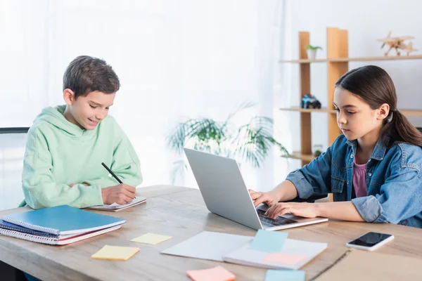 Positive Boy Writing Notebook Girl Typing Laptop While Studying Home — Stock Photo, Image