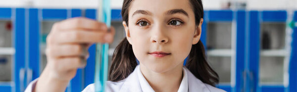 preteen girl holding blurred test tube in chemical laboratory, banner