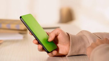 Evde yeşil ekranlı akıllı telefon kullanan bir kadın görüntüsü 